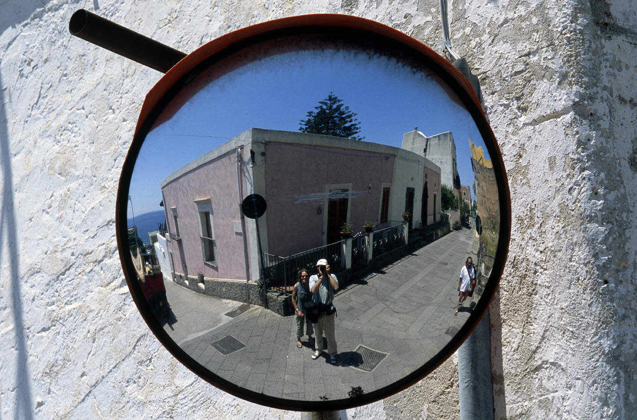eol06_268.jpg - Italie, îles Eoliennes Salina le photographe face à un miroir pour automobilistes à un carrefour Fuji Velvia 100 F
