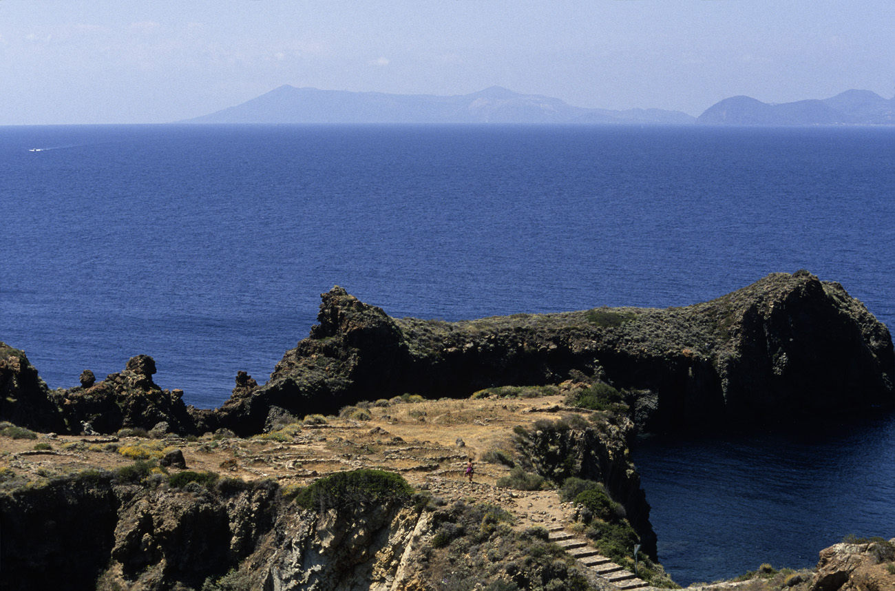 eol06_353.jpg - Italie, îles Eoliennes Panarea un site néolithique défendu naturellement par les falaises, dans un cadre étonnant face à Vulcano et Lipari que l'on distingue au loin Fuji Velvia 100 F